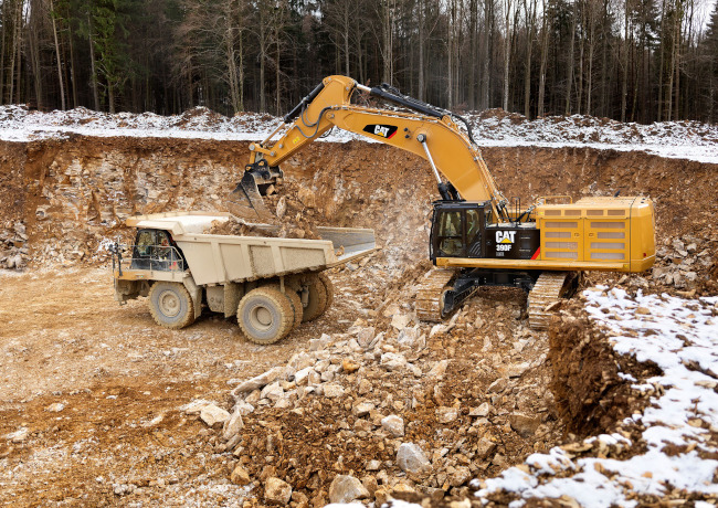A dump truck and an excavator digging a hole.