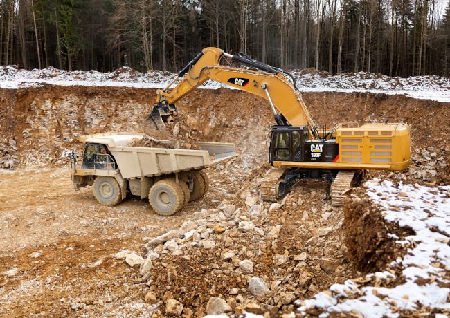 A dump truck and excavator digging a hole.